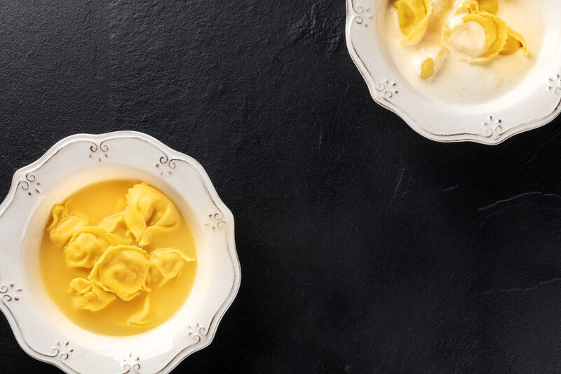 tagAlt.Tortellini with broth and cream sauce, Italian food on a black background with copy space