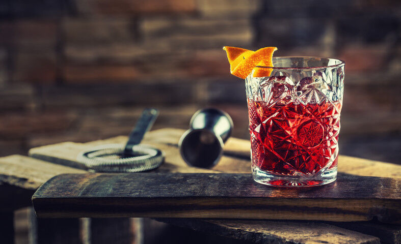 Cocktail Negroni on a old wooden board. Drink with gin, campari martini rosso and orange_20221010