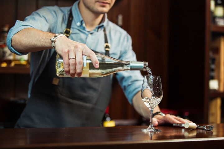 Sommelier versa vino bianco in bicchieri a stelo lungo