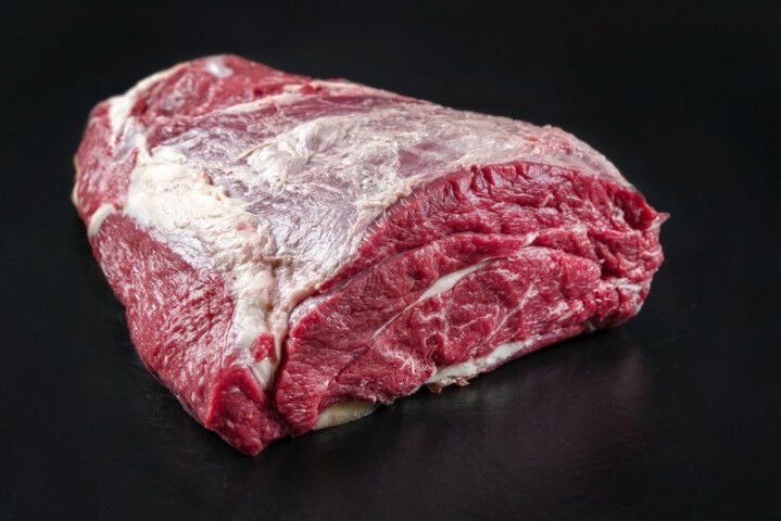 Raw dry aged wagyu beef shoulder clod roast as closeup on black background