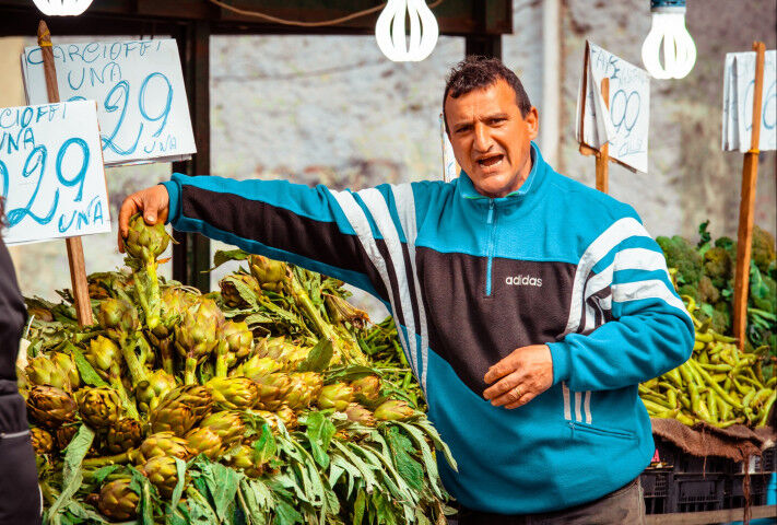 Vendor sells artichokes at famous local market Ballaro in Palermo, Italy