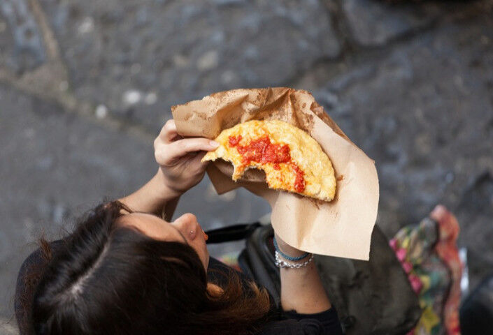 Woman photographed from above eating a pizza in Naples
